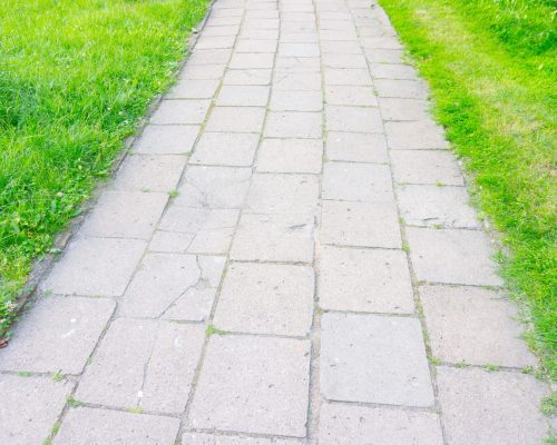 A high angle shot of footpath made of stone tiles surrounded by green grass